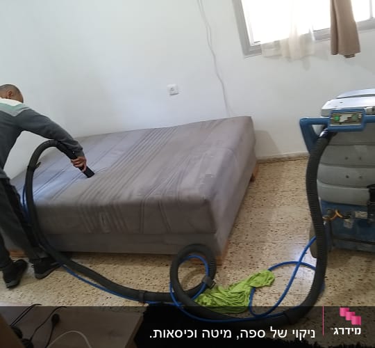 אדם מנקה מזרן עם שואב אבק תעשייתי
